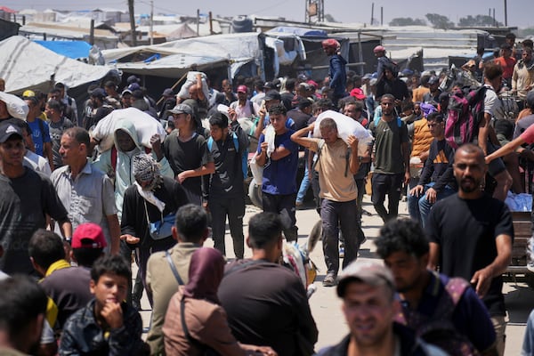 Palestinians carry bags containing food and humanitarian aid packages delivered by the Gaza Humanitarian Foundation, a U.S.-backed organization, in Rafah, southern Gaza Strip, Sunday, June 15, 2025. (AP Photo/Abdel Kareem Hana)