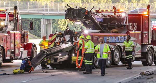 A wrecker leaving the scene of a tractor-trailer crash on I-285 North had its crane extended and became stuck under the Langford Parkway bridge. JOHN SPINK / JOHN.SPINK@AJC.COM