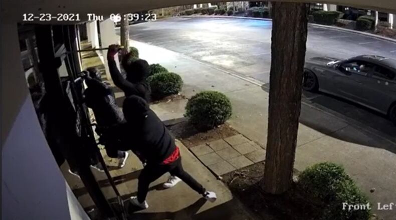 Masked burglars pry open the front doors of The Plug ATL during a Dec. 23 break-in at the film rental shop in Chamblee. The suspects eventually entered the store and stole $100,000 worth of camera and film equipment, according to authorities.