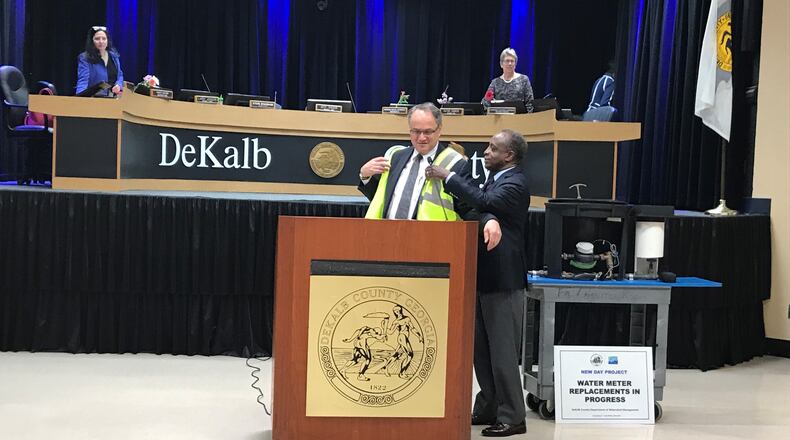 DeKalb County CEO Michael Thurmond (right) puts a DeKalb New Day Project work vest on Jeff Rader, presiding officer of the county commission after a presentation on the initiative during the meeting on March 12, 2019. (TIA MITCHELL/TIA.MITCHELL@AJC.COM)