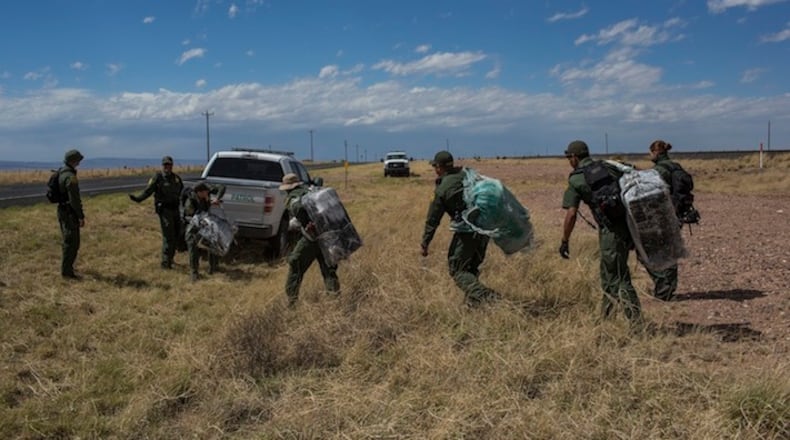 U.S. Border Patrol agents carry bales of marijuana they found along the highway near Ryan, Texas, about 20 miles from the US-Mexico border, Tuesday, March 28, 2017. One agent said "They (the smugglers) just leave it and come back another day. It's going to be sad when they come back for it." Drug interdiction is a core mission for the Border Patrol. (AP Photo/Rodrigo Abd)