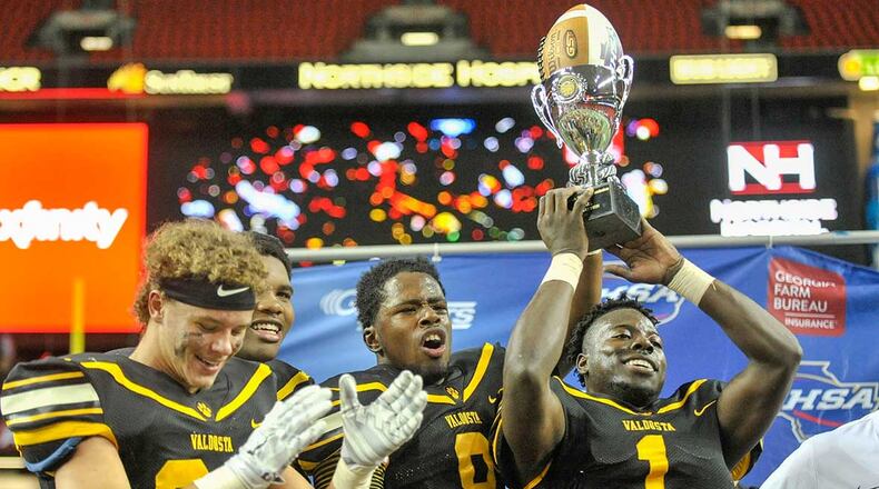 Valdosta seniors Wesley Veal (24, L-R), Devonnsha Maxwell (92), Jontae Baker (8), and Antwon Kincade hold their trophy high after beating Tucker 17-7 in the Class AAAAAA state title game at the Georgia Dome Friday.