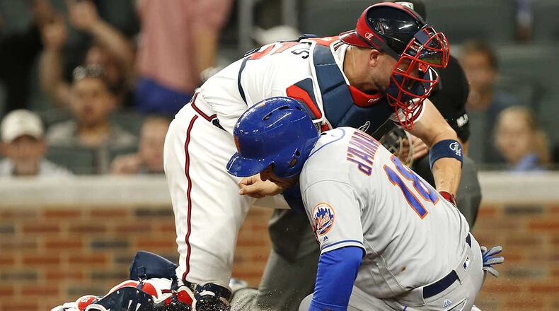 Travis d'Arnaud slides into home plate under the tag of Braves catcher Tyler Flowers in the fourth inning of Monday's game.