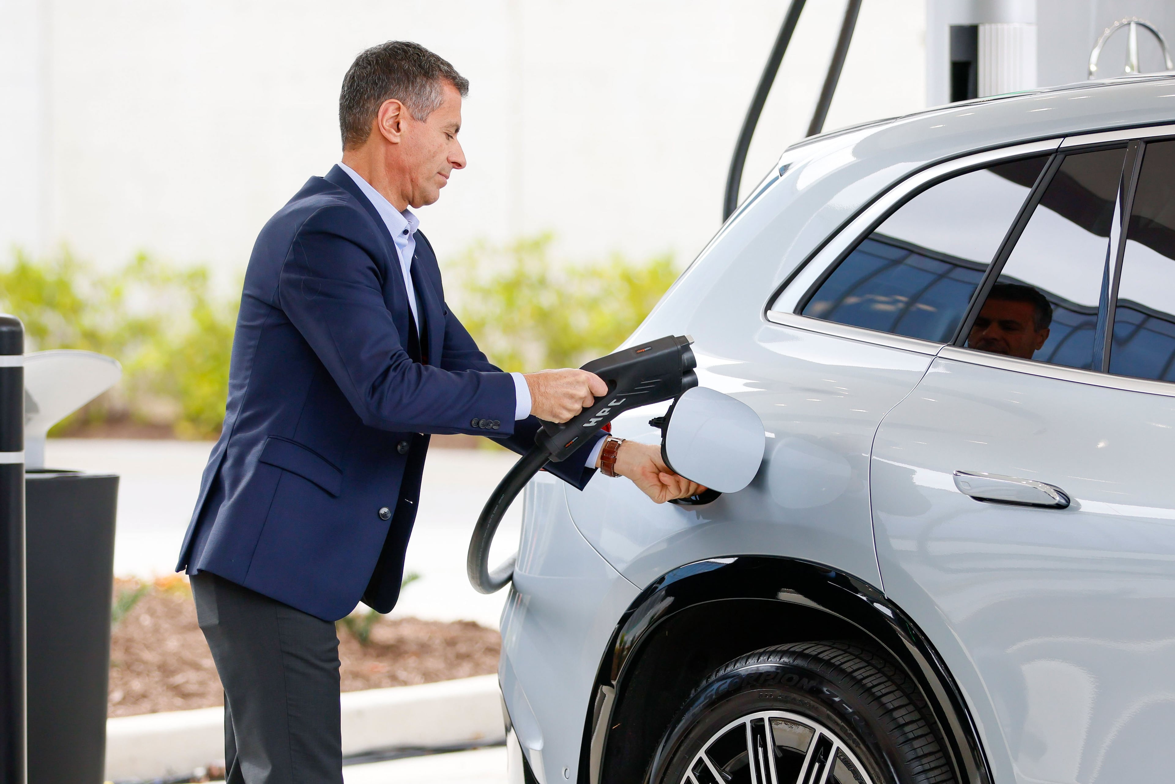 Dimitris Psillakis, then-president & CEO of Mercedes-Benz USA, plugs the electric charger into a car during the unveiling of the first-of-its-kind EV fast-charging hub.
(Miguel Martinez/AJC 2023)