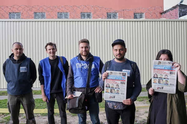 FILE - Belarusian journalists, from left, Svyatoslav Zorky, Alexey Sudnikov, Andrey Shavlyugo, Nikita Nedoverkov and Maria Eleshevich, pose after their release from a detention center, seen behind them, in Minsk, Belarus, on Sept. 4, 2020. (AP Photo, File)