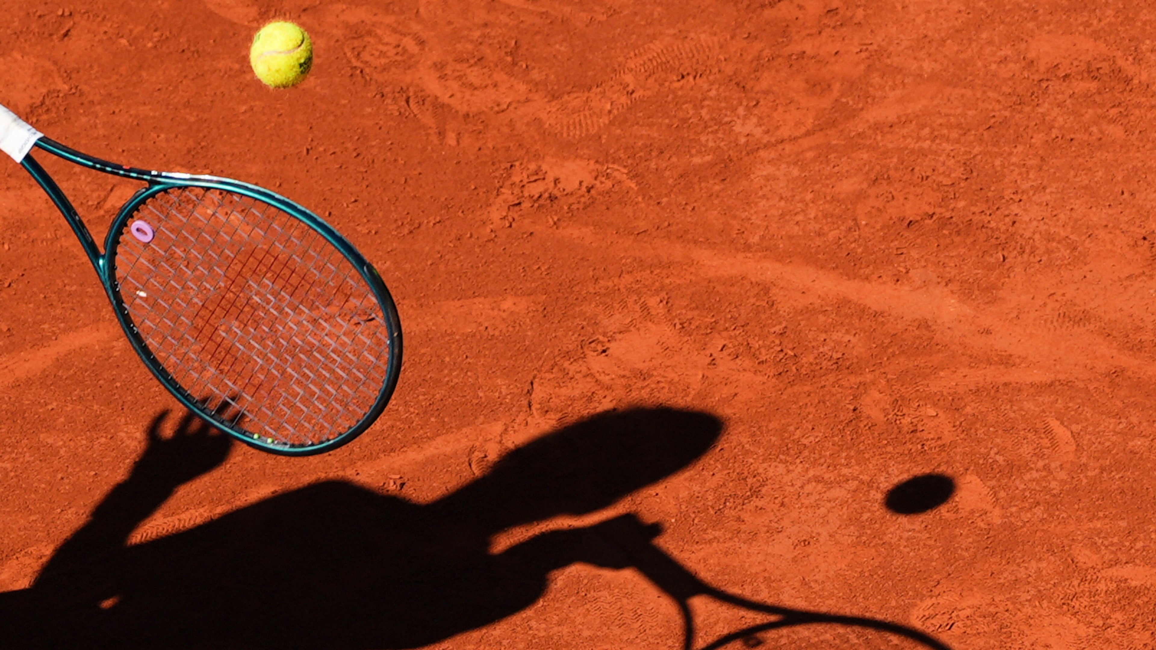 FILE - A player casts a shadow upon the court as they play a shot during the French Tennis Open, Friday, May 30, 2025, at the Roland-Garros stadium in Paris. (AP Photo/Lindsey Wasson, File)