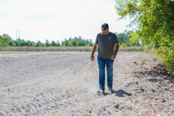 Multigenerational farmer Art Cothern walks across one of the fields on his farm outside Alma on Tuesday, April 21, 2026. Cothern's fields are directly next to land that has been cleared for solar panels, and he is concerned about the future of his family farm. (Miguel Martinez/AJC)