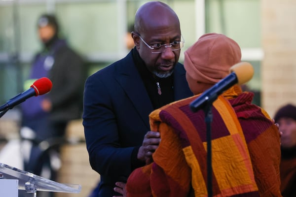 U.S. Sen. Raphael Warnock gifts an MLK Jr. pin to a Buddhist monk during a rest on his “Walk for Peace” in Decatur, Ga., on Tuesday, December 30, 2025. The monks started their walk in Texas and are on the way to Washington, D.C. (Abbey Cutrer/AJC)