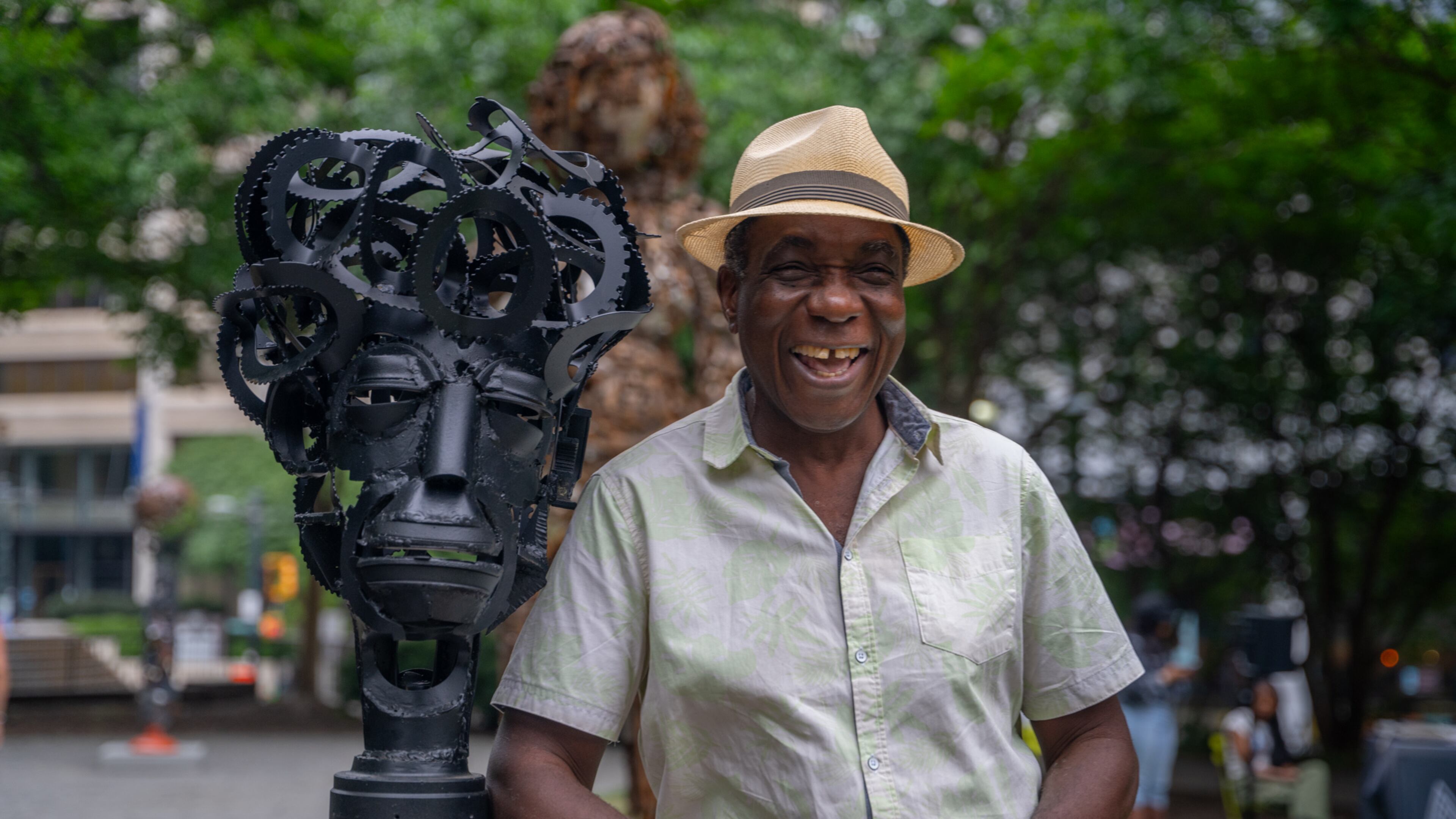 Alpharetta-based artist Olu Amoda leans against one of his discarded material sculptures. Seven of his works are on display in Woodruff Park until June 17. (Jeffrey Moustache/AJC)