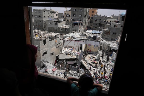 A child and a woman look as Palestinians search the rubble of a house targeted by an Israeli army strike that killed killing at least five members of the Abu Sahloul family in Khan Younis, in the southern Gaza Strip, Thursday, May 1, 2025. (AP Photo/Abdel Kareem Hana)