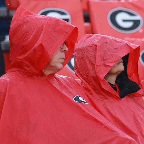 Georgia fans cover up from a heavy rain at kickoff against Texas A&M on Saturday, Nov. 23, 2019, in Athens. Saturday's Georgia–Austin Peay game was suspended around 4:15 p.m. after lightning was detected within 8 miles of Sanford Stadium. (AJC File)