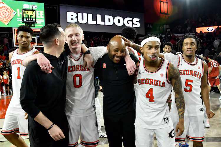 Georgia guard Blue Cain (front, second from left) and Georgia guard Marcus Millender (second from right) celebrate with coaching staff after Georgia beat Arkansas in an NCAA college basketball game at Stegeman Coliseum, Saturday, Jan. 17, 2026, in Athens. Georgia won 90-76 over Arkansas. (Hyosub Shin/AJC)