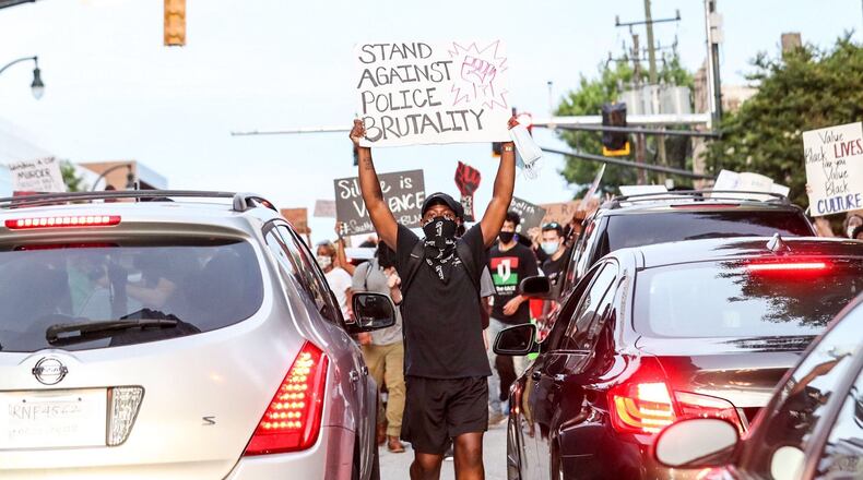 A demonstrator shows his sign to drivers stuck in traffic while heading down North Avenue in Atlanta.