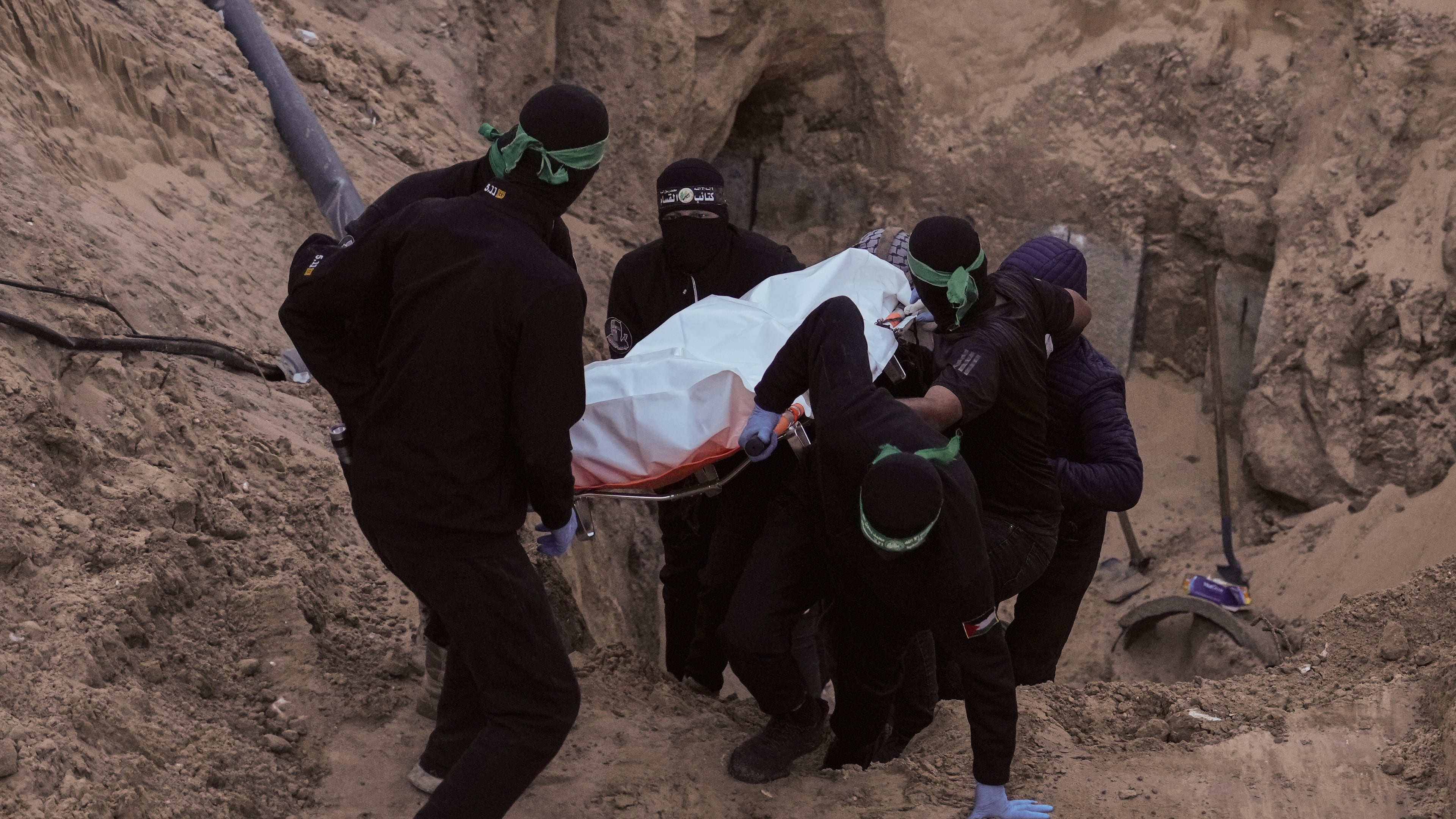 Hamas militants carry a white bag believed to contain a body, retrieved from a tunnel during a search for the remains of hostages in Hamad City, Khan Younis, southern Gaza, Tuesday, Oct. 28, 2025. (AP Photo/Jehad Alshrafi)