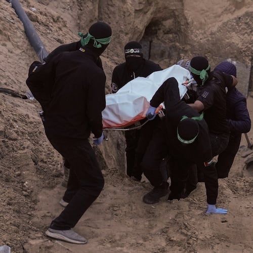 Hamas militants carry a white bag believed to contain a body, retrieved from a tunnel during a search for the remains of hostages in Hamad City, Khan Younis, southern Gaza, Tuesday, Oct. 28, 2025. (AP Photo/Jehad Alshrafi)