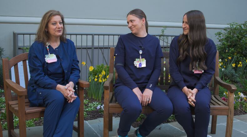 Sarah Rushton (left) sits with twin daughters, McKenna Roberts (center) and Mary Kate Harris, who are also nurses at Northeast Georgia Medical Center in Gainesville. Sarah gave birth to the twins at the hospital, where Sarah has spent 42 years and the twins have worked 10 years bringing new babies into the world. (Courtesy of Northeast Georgia Medical Center)