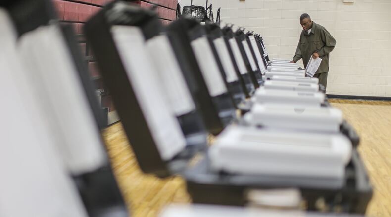 Poll manager Melvin Davis Jr. prepares voting machines at Henry W. Grady High School in Atlanta for the 2016 election. JOHN SPINK /JSPINK@AJC.COM