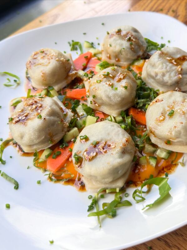 Plate of dumplings topped with herbs and sauce.