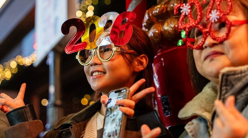 People pose for photographs at Lan Kwai Fong to celebrate the start of 2026 in the Central district of Hong Kong, on Wednesday, Dec. 31, 2025. (AP Photo/Chan Long Hei)
