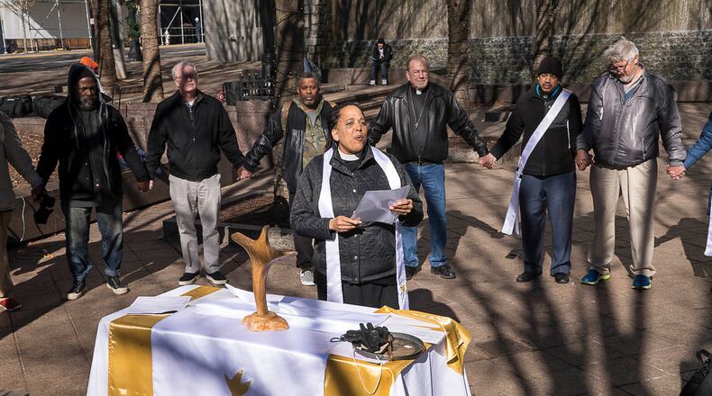 Reverend Kenya Thompson leads prayer during a Church of the Common Ground Christmas Eve service for the homeless at Woodruff Park in Atlanta. (ALYSSA POINTER/ALYSSA.POINTER@AJC.COM)