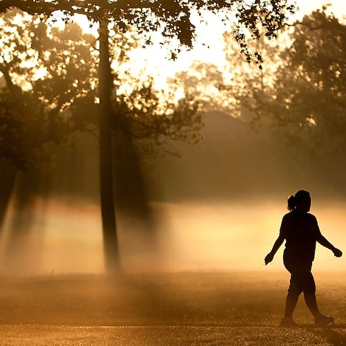 FILE - A woman walks down a trail as fog looms at Montie Beach Park in Houston, on Monday, Oct. 17, 2011. (Cody Duty/Houston Chronicle via AP, File)