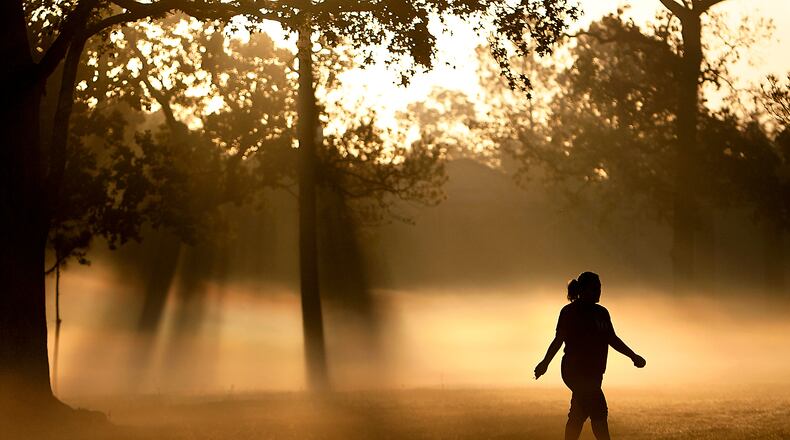 FILE - A woman walks down a trail as fog looms at Montie Beach Park in Houston, on Monday, Oct. 17, 2011. (Cody Duty/Houston Chronicle via AP, File)