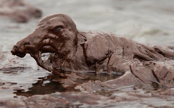 FILE - A bird is mired in oil on the beach at East Grand Terre Island along the Louisiana coast on June 3, 2010. (AP Photo/Charlie Riedel, File)