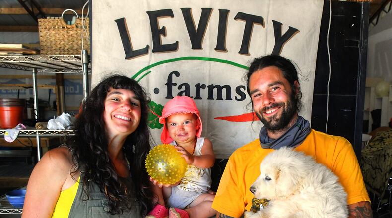 Ilana and Zach Richards, with their daughter Harlyn and new pup (a then-9-week-old Great Pyrenees named Mulch), pose in the barn before a tour of Levity Farms in Madison. Chris Hunt for The AJC