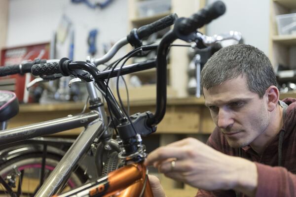 Andrej Ciho, 35, the manager of South Atlanta Bike Shop, repairs the handlebars on a customer’s bike. South Atlanta Bike Shop temporarily employs students from around the area. DAVID BARNES / SPECIAL