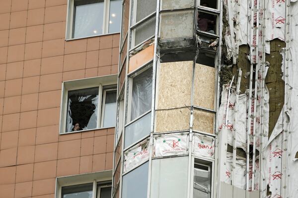 A woman speaks on the phone near a window of an apartment block of the Mirax Park residential complex damaged in a reported Ukrainian drone attack on Vernadsky Avenue in Moscow, Russia, Thursday, May 29, 2025. (AP Photo)