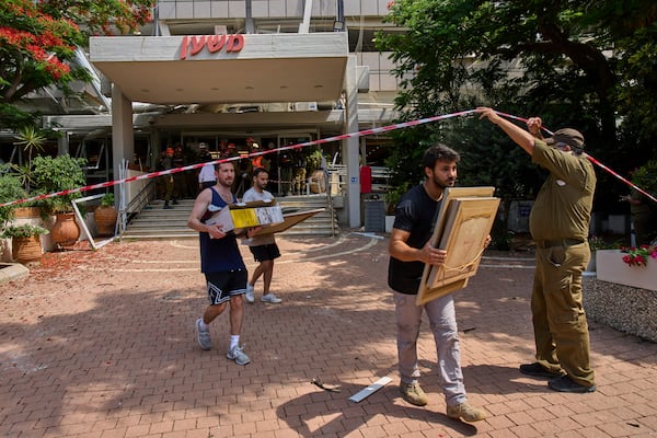 People recover items from a building damaged in an Iranian missile strike in Tel Aviv, Israel, Sunday, June 22, 2025. (AP Photo/Bernat Armangue)