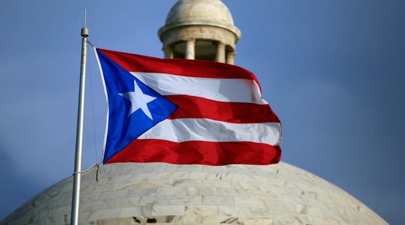 FILE - A Puerto Rican national flag flies in front of the Capitol building in San Juan, Puerto Rico, July 29, 2015. (AP Photo/Ricardo Arduengo, File)