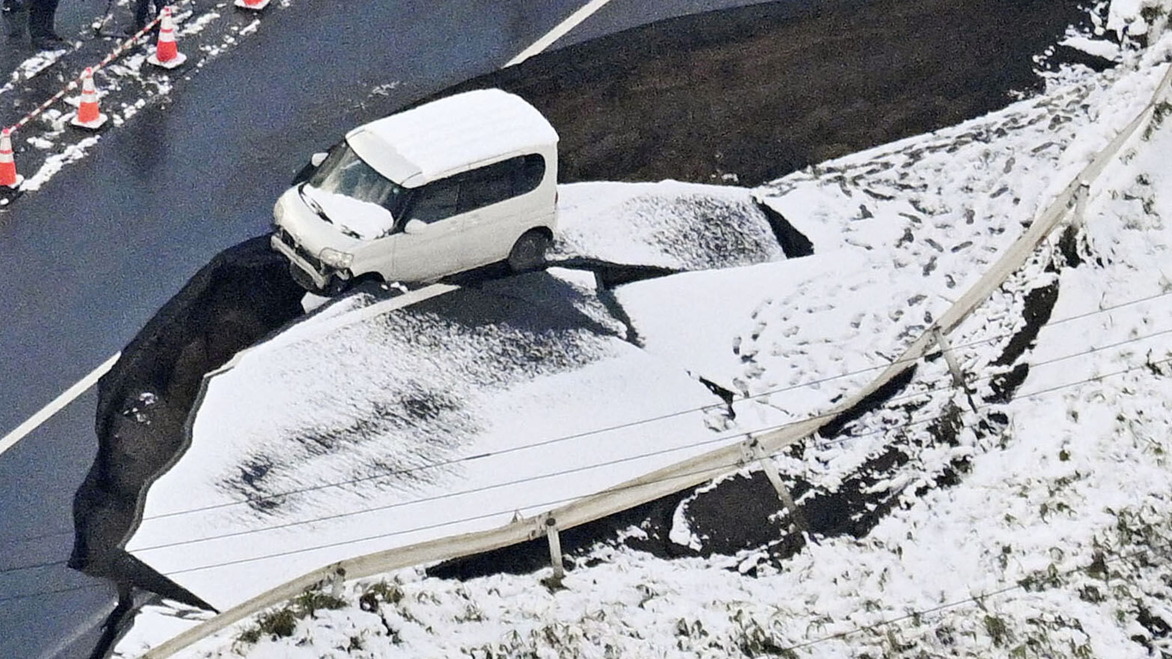 This aerial photo shows a vehicle sitting on a damaged road in Tohoku town, Aomori prefecture, northern Japan Tuesday, Dec. 9, 2025, following a powerful earthquake on late Monday. (Kyodo News via AP)
