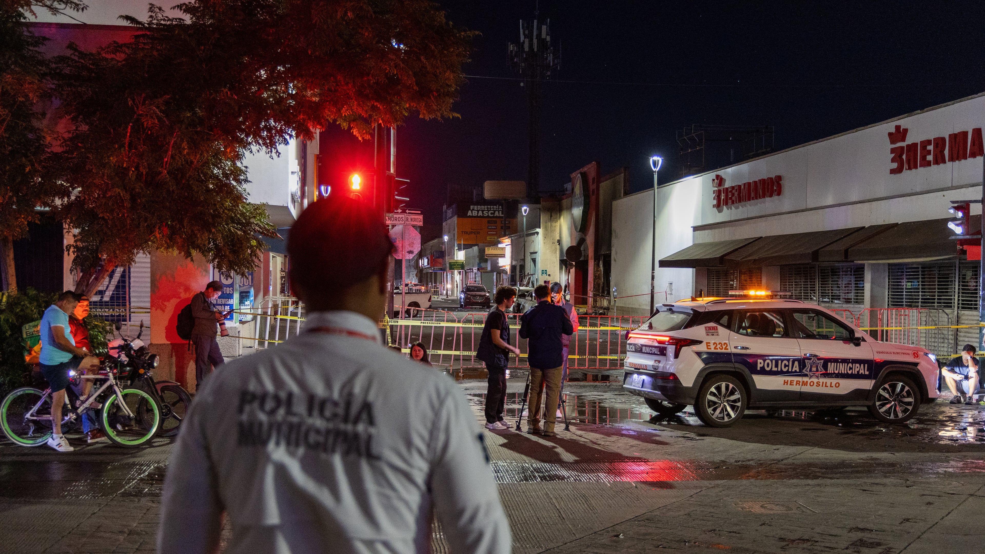 Policeman stands near a convenience store destroyed by a fire in Hermosillo, Sonora state, Mexico, Saturday, Nov. 1, 2025. (AP Photo/Abraham Tellez)
