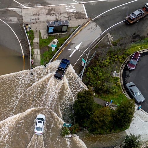 Vehicles drive on a flooded road during a king tide event in Corte Madera, Calif., Saturday, Jan. 3, 2026. (Stephan Lam/San Francisco Chronicle via AP)