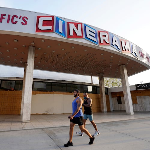 FILE - Pedestrians walk past the boarded up and closed Cinerama Dome movie theater in Los Angeles on April 12, 2021. (AP Photo/Chris Pizzello, File)