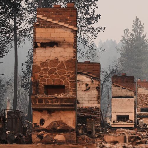 Chimneys are the only structures remaining in a residential neighborhood after a wildfire hit the northern part of Spokane, Wash., Monday, Aug. 3, 2026. (AP Photo/Lindsey Wasson)