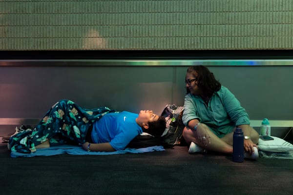 Xavier Williams (left) and Monica Paz try to rest at Hartsfield-Jackson Atlanta International Airport following a global technology outage that hampered airlines and other industries. (Arvin Temkar/AJC 2024)