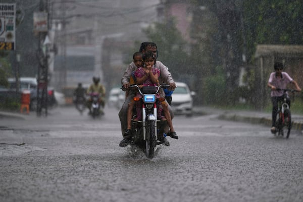 FILE - A motorcyclist with his family drive on a street during heavy rainfall in Rawalpindi, Pakistan, June 27, 2025. (AP Photo/Anjum Naveed, File)