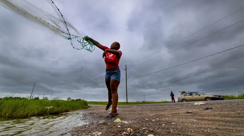 With skies darkening ahead of Tropical Storm Bertha, Latia Ancar practices her casting while she and a friend wait for the storm-driven tidal surge about 50 miles south of New Orleans on Wednesday, July 22, 2026, hoping it will bring more fish. (Chris Granger/The Times-Picayune/The New Orleans Advocate via AP)