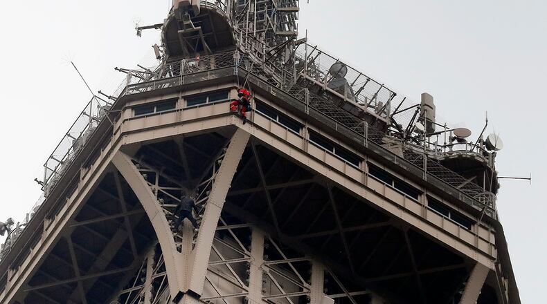 A rescue worker hangs from the Eiffel Tower Monday, May 20, 2019 in Paris. The Eiffel Tower has been closed to visitors after a person has tried to scale it. (AP Photo/Michel Euler)