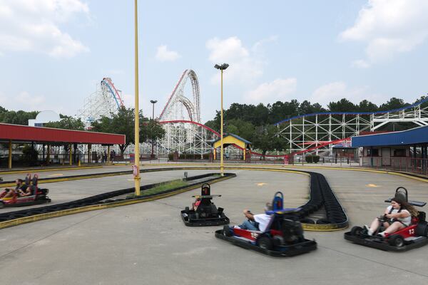 Visitors ride go-karts at Fun Spot in Fayetteville. The park's biggest attraction, a 154-foot-tall roller coaster, is in the background. (Arvin Temkar/AJC)