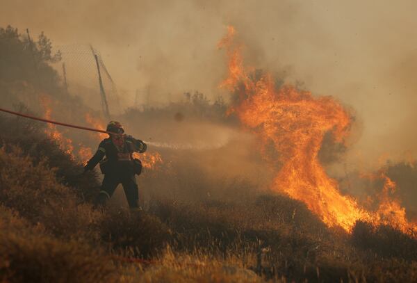 A firefighter uses a hose as he tries to extinguish the blaze near the town of Ierapetra on the south coast of Crete island, Greece, Thursday July 3, 2025, as a fast-moving wildfire prompted authorities to clear villages and coastal areas, officials said. (InTime News via AP)