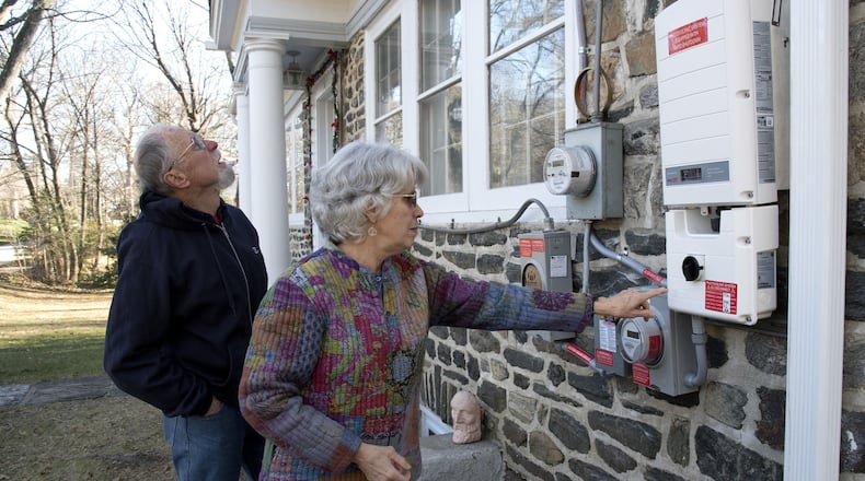 Sue and George Edwards look at the electric meters, control panel and inverter installed on the side of their Swarthemore home when they had solar panels installed on their roof in early December. The Edwards were part of a group of 50 families in the Media area to sign up to have solar systems installed on their houses. But much to their chagrin, nearly a third of the 50 households that signed up were not permitted to hook their solar systems into the Peco network because the utility said the grid would be destablized on December 20, 2016. (Clem Murray/The Philadelphia Inquirer/TNS)