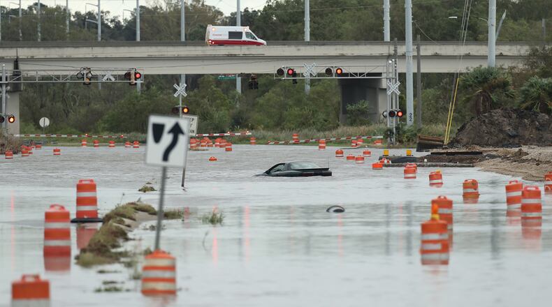 An ambulance responding to a call passes a swamped vehicle on President Street that tried to cross flood waters to Tybee Island during Hurricane Matthew on Saturday, Oct. 8, 2016, in Savannah. Curtis Compton /ccompton@ajc.com