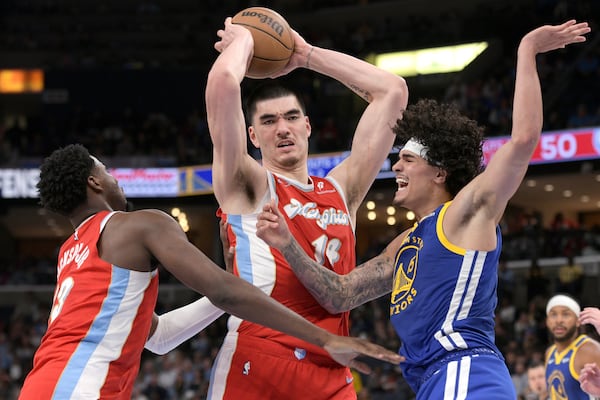 Memphis Grizzlies center Zach Edey (14) handles the ball between forward Jaren Jackson Jr. (13) and Golden State Warriors forward Gui Santos (15) in the first half of an NBA basketball game Tuesday, April 1, 2025, in Memphis, Tenn. (AP Photo/Brandon Dill)