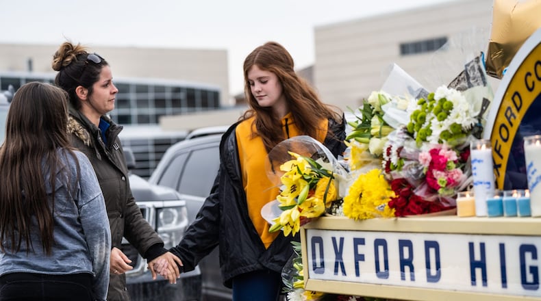 People get emotional while standing at a memorial at an entrance to Oxford High School on Dec. 1, 2021, following an active shooter situation at Oxford High School that left four students dead and multiple others with injuries. (Ryan Garza/Detroit Free Press/TNS)
