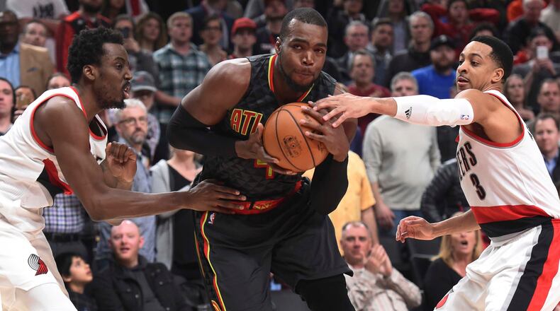Atlanta Hawks forward Paul Millsap drives to the basket on Portland Trail Blazers forward Al-Farouq Aminu and guard C.J. McCollum in the second half of an NBA basketball game in Portland, Ore., Monday, Feb 13, 2017. Atlanta won in overtime 109-104. (AP Photo/Steve Dykes)