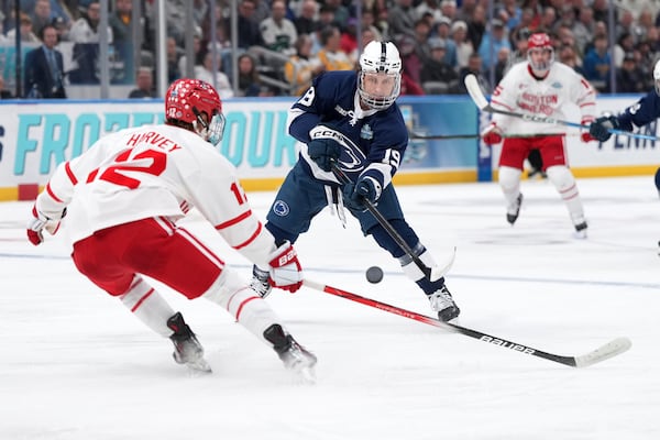 Penn State's Dane Dowiak (19) passes around Boston University's Jack Harvey (12) during the first period in a semifinal game in the NCAA Frozen Four men's college hockey tournament, Thursday, April 10, 2025, in St. Louis (AP Photo/Jeff Roberson)