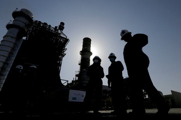 FILE - Saudi Aramco engineers walk in front of a gas turbine generator at Khurais oil field during a tour for journalists, outside of Riyadh, Saudi Arabia on June 28, 2021. (AP Photo/Amr Nabil, File)